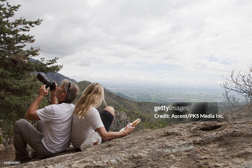 Couple rest on rock with camera and pannini