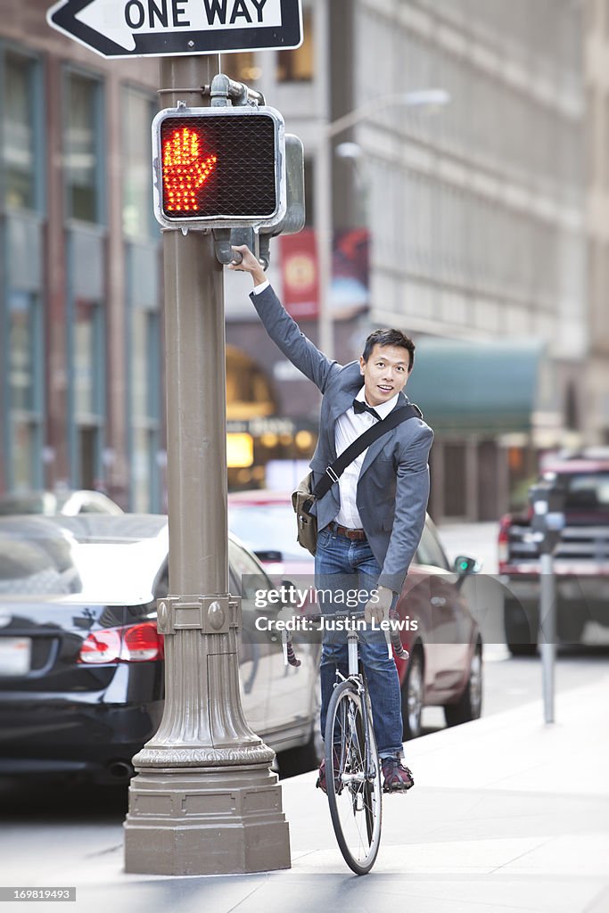 Young male reaching for stop light in the city