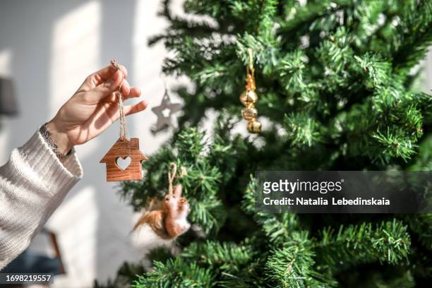 toy house in woman's hand - decoration of christmas tree and dreams of home - homeowners decorate their houses for christmas stockfoto's en -beelden