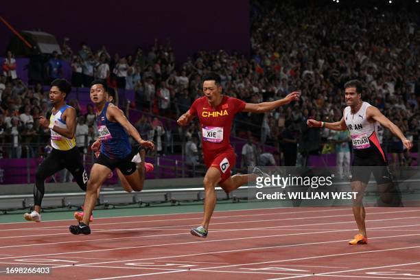 China's Xie Zhenye crosses the finish line to win the men's 100m final athletics event during the 2022 Asian Games in Hangzhou in China's eastern...