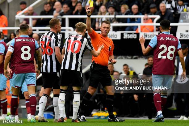 Newcastle United's English midfielder Anthony Gordon receives a yellow card by referee Thomas Bramall during the English Premier League football...