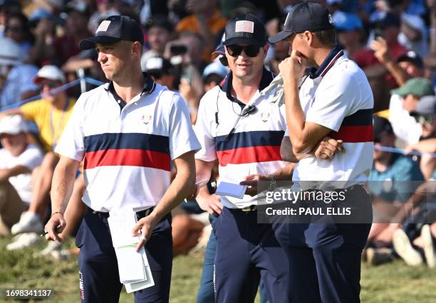 Captain, Zach Johnson speaks with US golfer, Justin Thomas and US golfer, Jordan Spieth on the green during their four-ball match on the second day...