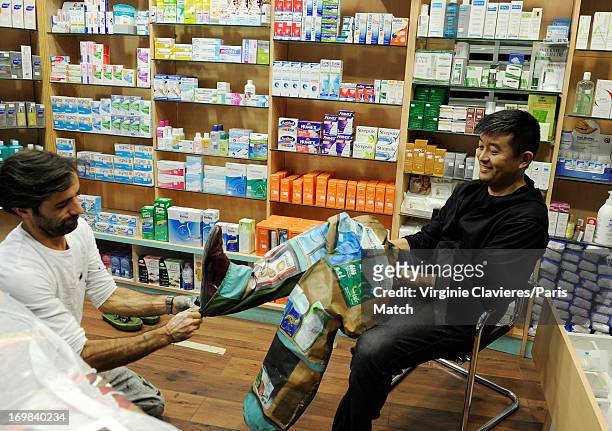 Performance artist Liu Bolin is photographed for Paris Match during preparation for a work which takes place at a pharmacist's and is a commentary on...