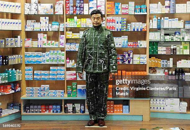 Performance artist Liu Bolin is photographed for Paris Match during preparation for a work which takes place at a pharmacist's and is a commentary on...