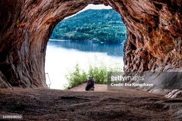 a cave in the mountain with a view to the lake - hollow stock pictures, royalty-free photos & images