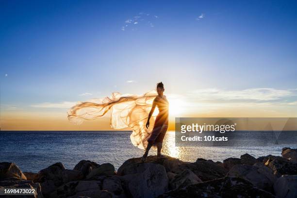 ballerina dancing with thin nylon on the rocks. - glamour live show fashion shows stock pictures, royalty-free photos & images