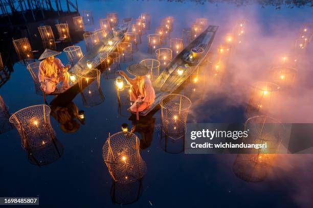 fisherman with traditional fish trap at night, inle lake, myanmar - birmaanse cultuur stockfoto's en -beelden