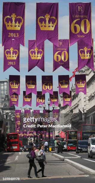 People walk across the street as flags fly over Regent Street to celebrate the 60th anniversary of the Coronation of Queen Elizabeth II on June 3,...