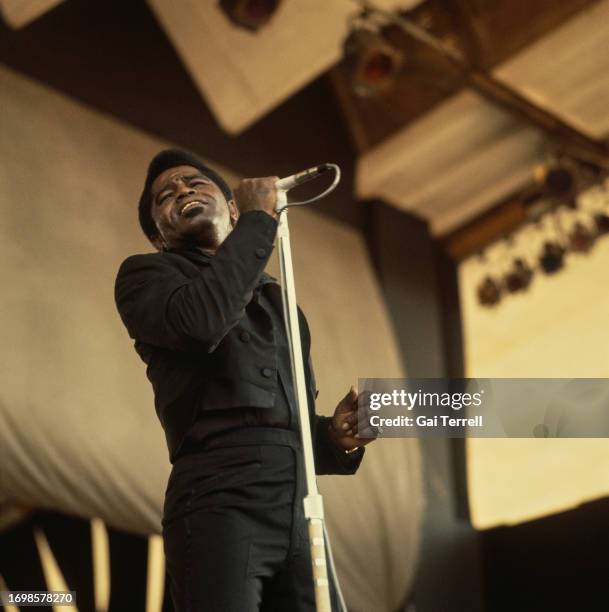American singer and musician James Brown holding a microphone mounted on a microphone stand as he performs in concert at the Newport Jazz Festival in...