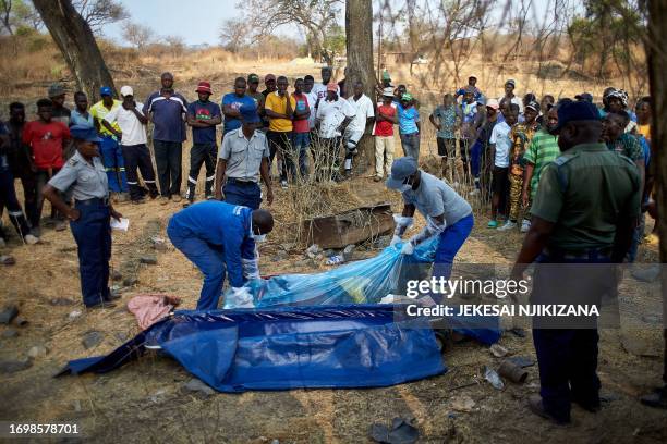 Graphic content / A crown gathers to observe a rescue team carrying the body of a miner after a gold mine shaft collapsed at the Bay Horse mine in...