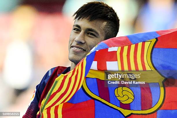 Neymar looks on as he holds a FC Barcelona flag during his official presentation as a new player of FC Barcelona at Camp Nou Stadium on June 3, 2013...