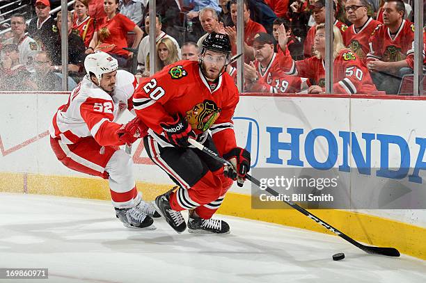 Brandon Saad of the Chicago Blackhawks approaches the puck as Jonathan Ericsson of the Detroit Red Wings pushes from behind in Game Seven of the...