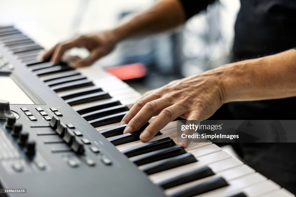 Musician man playing on synthesizer keyboard piano keys, male hands on synthesizer. Playing synthesizer on concert stage.