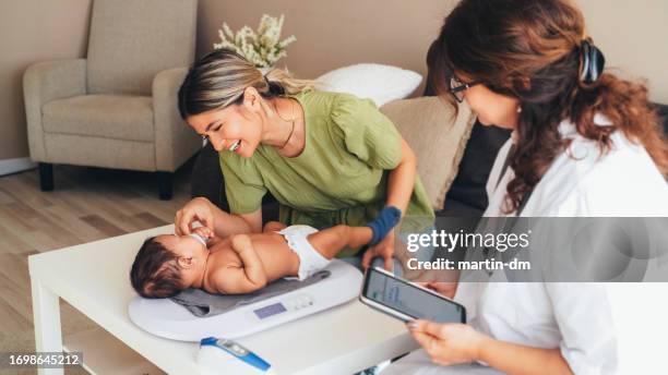 médico visitando a la madre joven en casa para el chequeo de rutina del recién nacido - comadrona fotografías e imágenes de stock