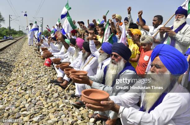 Agitating farmers holding demonstration by begging with earthen bowls during third day of 'rail roko' stir at the railway track at Village Devidas...