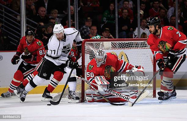 Goaltender Corey Crawford and Brent Seabrook of the Chicago Blackhawks defend their net as Jeff Carter of the Los Angeles Kings brings the puck...