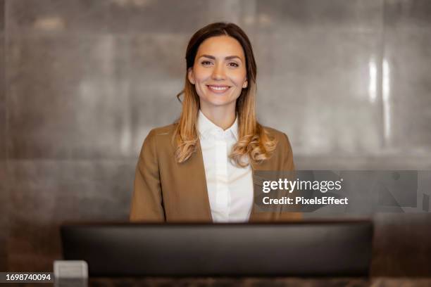 smiling female receptionist looking at camera - concierge stock pictures, royalty-free photos & images