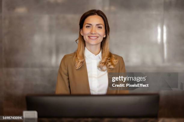 smiling female receptionist looking at camera - hotel occupation stock pictures, royalty-free photos & images