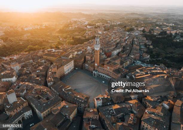 aerial view of torre del mangia (mangia tower) in piazza del campo (campo square) in siena, tuscany, italy. drone shot at sunrise - praça do campo imagens e fotografias de stock