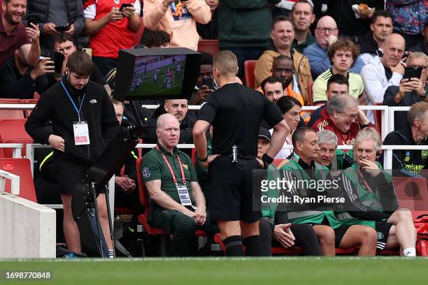 Referee Robert Jones checks the VAR screen for a handball by Cristian Romero of Tottenham Hotspur during the Premier League match between Arsenal FC...