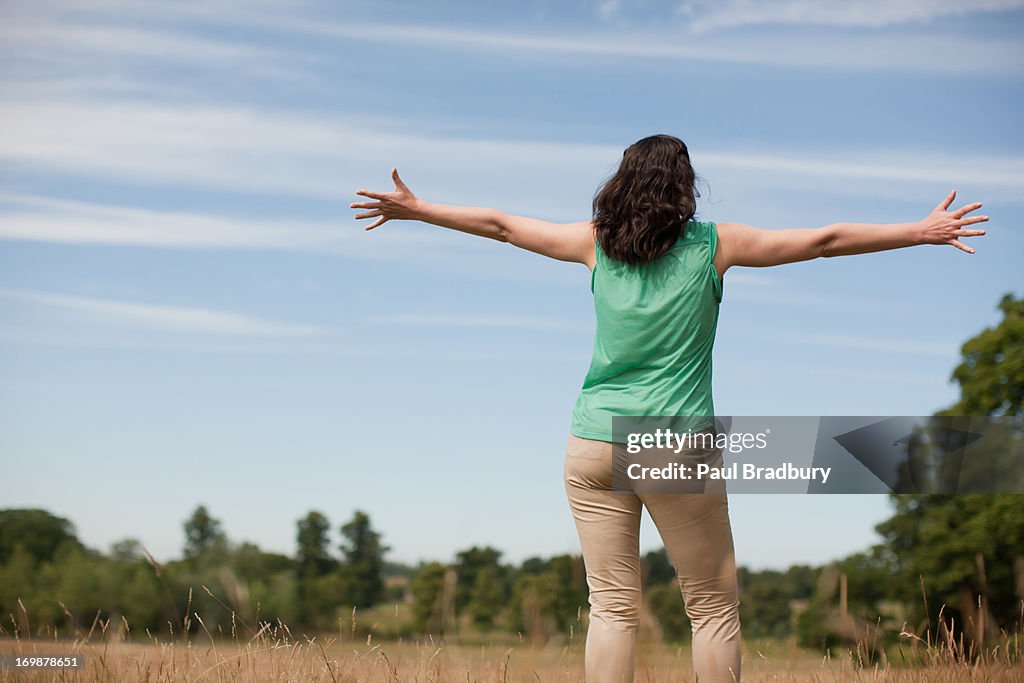 Woman with arms outstretched in sunny rural field