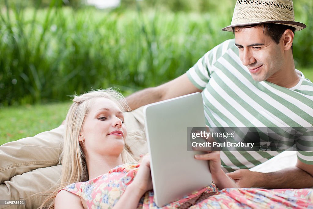 Young couple using digital tablet in park