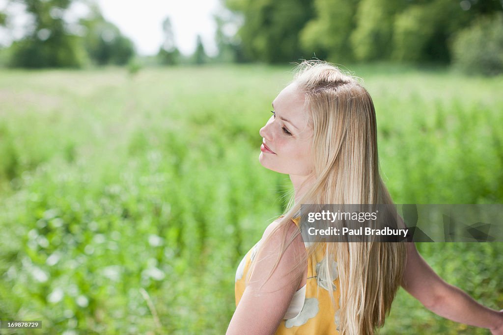 Smiling woman with arms outstretched in rural field