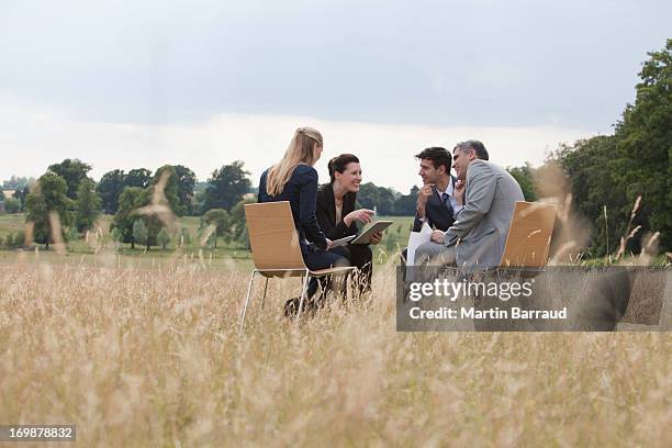 gens d'affaires ayant une réunion à l'extérieur - small group sitting in grass photos et images de collection