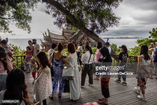 Tourists take photos of The Sanctuary of Truth Museum on September 24, 2023 in Pattaya, Thailand. Starting on September 25, tourists from China and...