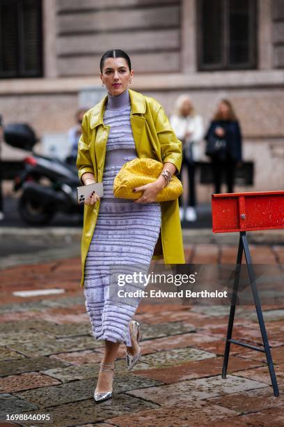 Guest wears a yellow pvc shiny rain coat / trench coat, a purple ribbed wool turtleneck fluffy midi / long dress, a yellow woven leather Bottega...