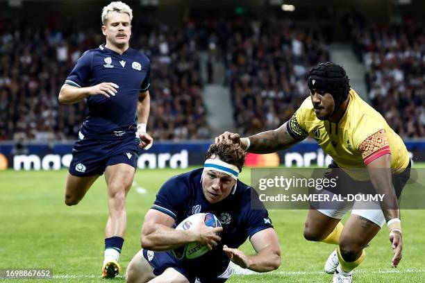 Scotland's flanker Hamish Watson dives across the line to score a try as Romania's outside centre Jason Tomane attempts to tackle him during the...