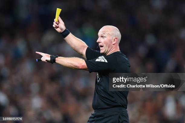 Referee Simon Hooper shows a yellow card during the Premier League match between Tottenham Hotspur and Liverpool FC at Tottenham Hotspur Stadium on...