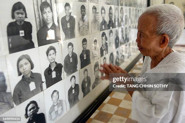 Cambodian woman reacts and gestures as she looks at portrait photos of victims of the Khmer Rouge regime displayed for tourists at the Tuol Sleng...