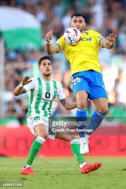 Maximiliano Gomez of Cadiz is challenged by Marc Bartra of Real Betis during the LaLiga EA Sports match between Real Betis and Cadiz CF at Estadio...