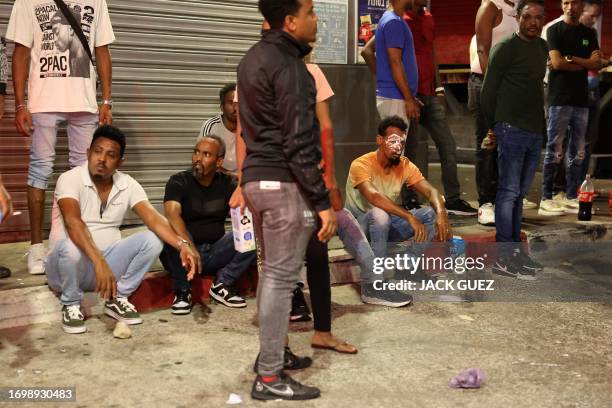 Men sit on the pavement at the scene of a violent fight between a group of Eritrean nationals in the coastal city of Netanya on September 30, 2023.