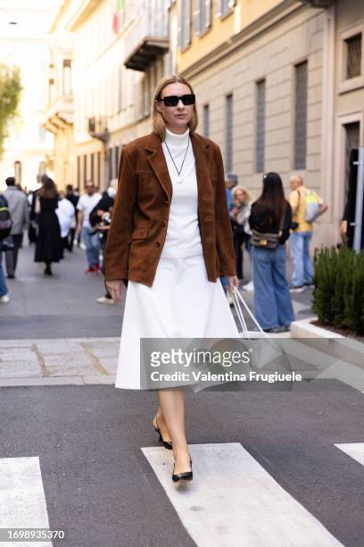 Guest is seen wearing a brown suede jacket over a white dress outside Giorgio Armani show during the Milan Fashion Week - Womenswear Spring/Summer...