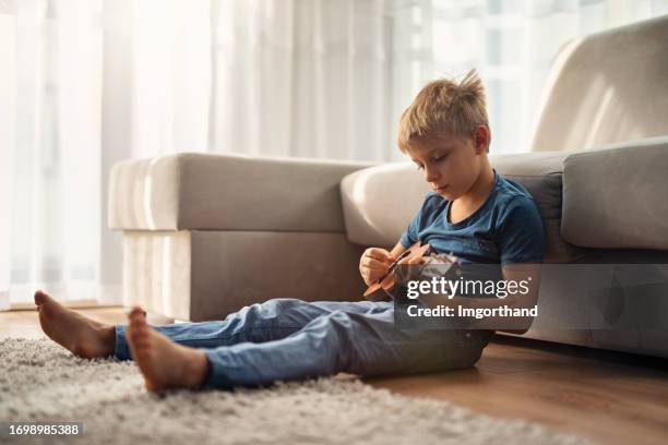cute little boy sitting on the floor and playing little guitar - blue acoustic guitar stock pictures, royalty-free photos & images
