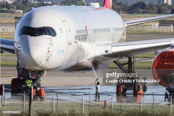 Man sprays water on an Airbus A330 around the Airbus area at the Toulouse-Blagnac airport in Toulouse, southwestern France, on September 30, 2023.