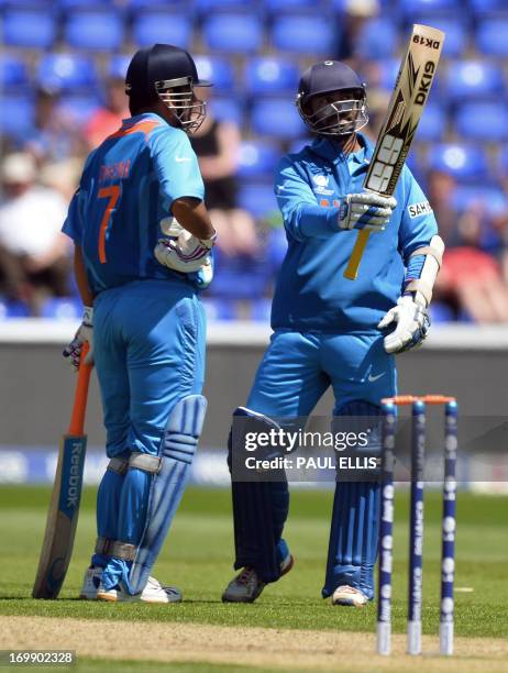 India's Dinesk Karthik stands beside captain Mahendra Singh Dhoni as he celebrates his half century during the warm-up cricket match ahead of the...