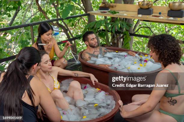 a couple takes an ice bath while their friends support them to endure the cold - bad breath stockfoto's en -beelden