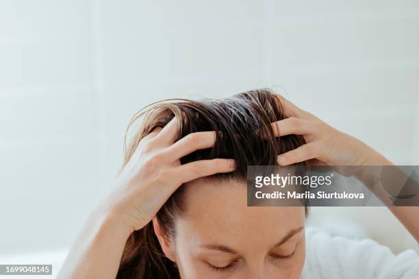 woman delicately doing massage of her scalp with cosmetic oil. - acomia - fotografias e filmes do acervo