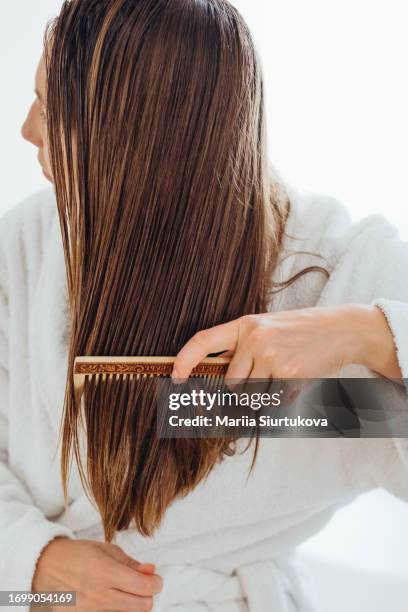 girl carefully combing her hair with a wooden comb. - glitter hair stock-fotos und bilder
