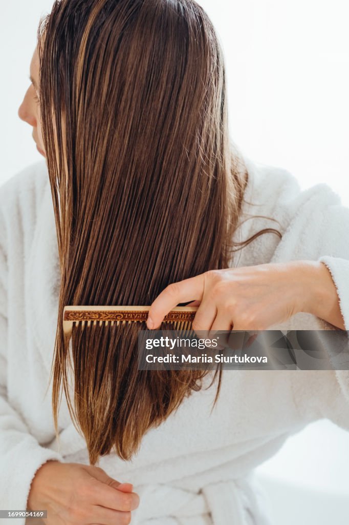 Girl carefully combing her hair with a wooden comb.