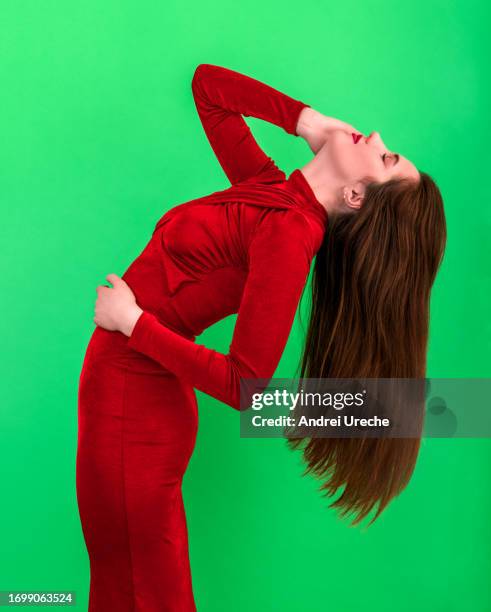 woman wearing red dress and with beautiful long hair, isolated on a green background - long sleeved stockfoto's en -beelden