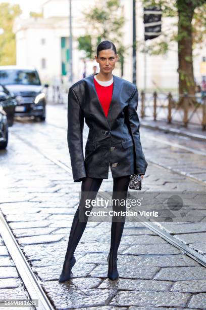 Bianca Balti wears black tailored oversized leather jacket, tights, red shirt, bag outside The Attico during the Milan Fashion Week - Womenswear...