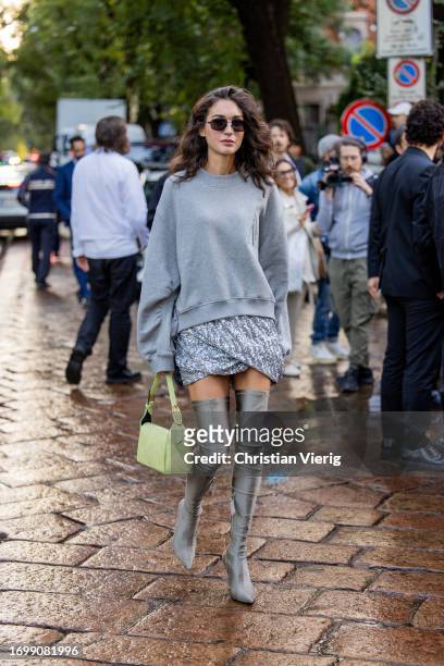 Diletta Bonaiuti wears grey oversized sweater, silver skirt, over knees boots, yellow green bag outside The Attico during the Milan Fashion Week -...