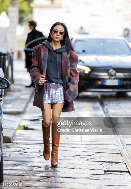 Yoyo Cao wears grey hoody, oversized blazer, silver mini skirt, brown boots outside The Attico during the Milan Fashion Week - Womenswear...