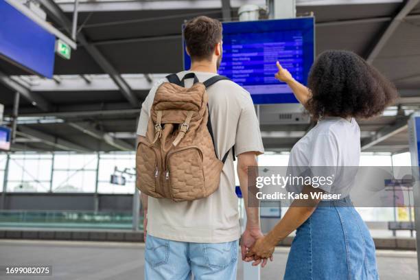 young couple at subway station looking at information board - flughafen wien stock-fotos und bilder