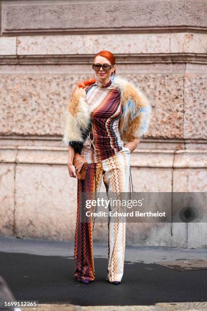 Guest wears sunglasses, a fluffy colored jacket, a gathered turtleneck colored top with geometric patterns, flared pants, a brown leather bag,...