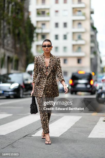 Guest wears sunglasses, a golden chain necklace, bras, a brown leopard print oversized blazer jacket, suit pants, a fluffy black bag, shoes, outside...